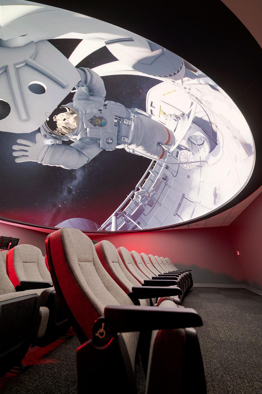 天文馆的座位和穹顶，屏幕上有太空行走的图像